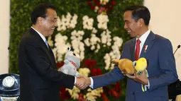 Presiden Jokowi bersalaman dengan PM China Li Keqiang sambil memegang maskot Asian Games 2018 di Istana Bogor (7/5). (AFP/Pool/Dita Alangkara)