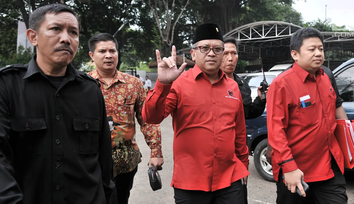 Sekjen PDIP Hasto Kristiyanto (tengah) menyapa awak media saat tiba untuk medaftarkan bakal caleg ke  KPU, Jakarta, Selasa (17/7). Salam metal menjadi ciri khas PDIP karena menggambarkan nomor urut tiga. (Merdeka.com/Iqbal Nugroho)