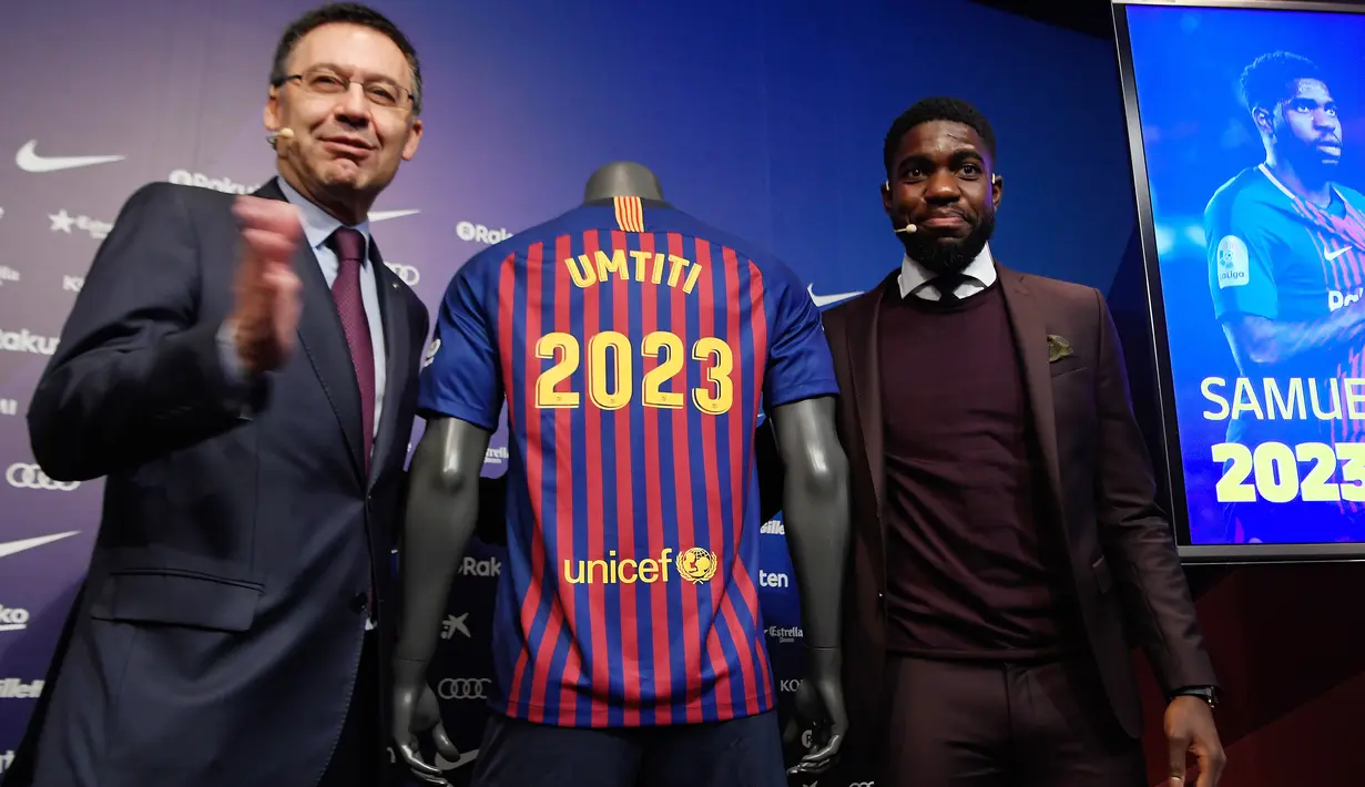 Bek Prancis, Samuel Umtiti dan Presiden Barcelona Josep Maria  berpose di samping jersey Barcelona pada pengumuman perpanjangan kontraknya di stadion Camp Nou, Senin (4/6). Umtiti memperpanjang kontraknya bersama Barcelona hingga 2022. (LLUIS GENE/AFP)