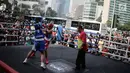Dua petinju saling melepaskan pukulan pada pertandingan tinju amatir saat Car Free Day di kawasan Bundaran HI, Jakarta, Minggu (29/4). Pertandingan tanpa pemenang ini digelar Persatuan Tinju Amatir Indonesia (Pertina). (Liputan6.com/Faizal Fanani)