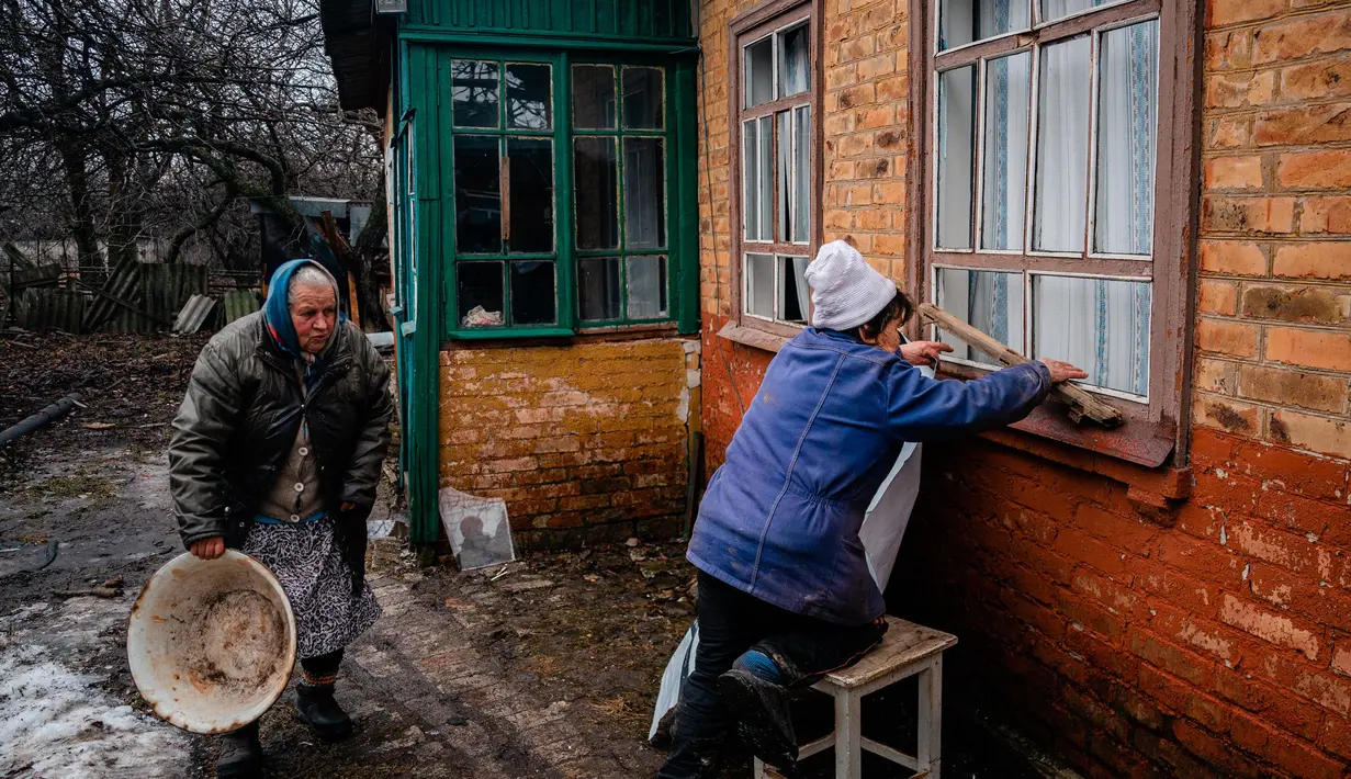 Para wanita lanjut usia bekerja untuk memperbaiki jendela yang pecah setelah penembakan di Chasiv Yar, dekat Bakhmut pada 28 Februari 2023. Presiden Ukraina Volodymyr Zelensky mengatakan situasi di kota Bakhmut, di garis depan timur menjadi semakin sulit setalah pasukan Rusia berusaha merebut kota itu selama lebih dari enam bulan. (Dimitar DILKOFF/AFP)