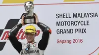 Anak didik Valentino Rossi, Francesco Bagnaia (Aspar Mahindra), mengangkat trofi juara di podium usai memenangi balapan Moto3 Malaysia di Sirkuit Sepang, Minggu (30/10/2016). (GPOne)