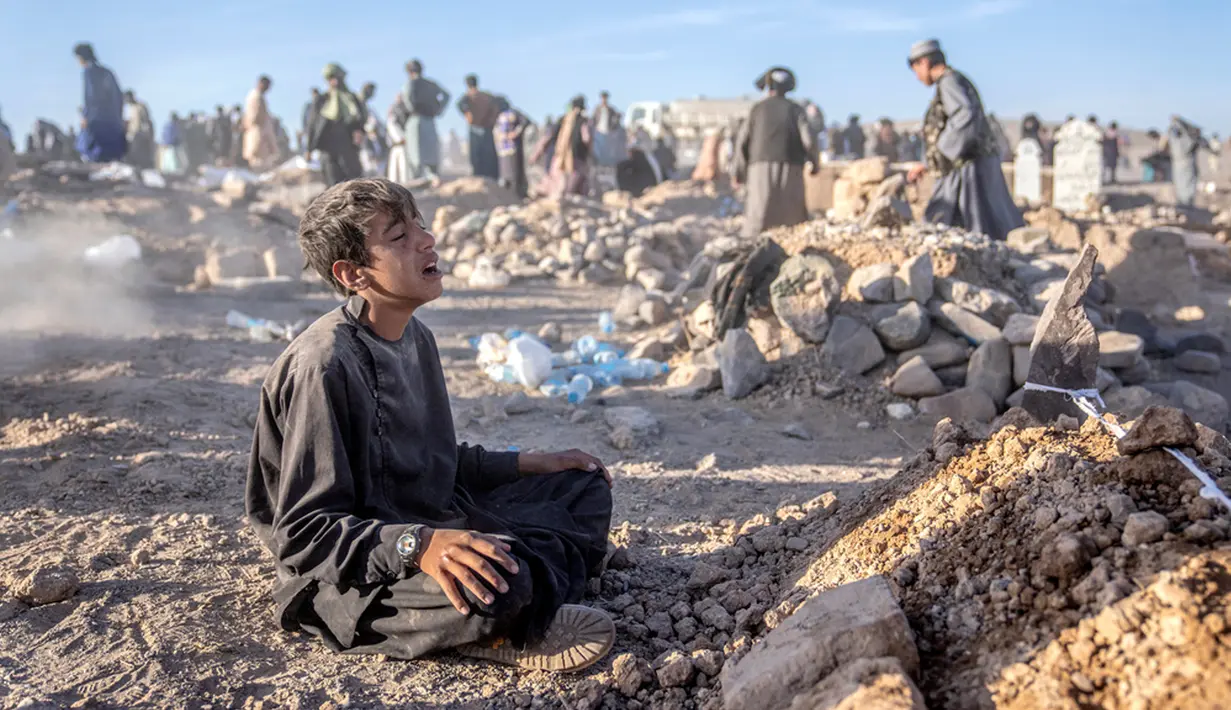 Seorang anak laki-laki berduka di samping makam adik laki-lakinya yang meninggal akibat gempa bumi di Distrik Zenda Jan, Provinsi Herat, sebelah barat Afghanistan, Senin (9/10/2023). Gempa mematikan yang terjadi pada Sabtu lalu menewaskan dan melukai ribuan orang serta menghancurkan rumah-rumah yang tak terhitung jumlahnya. (AP Photo/Ebrahim Noroozi)