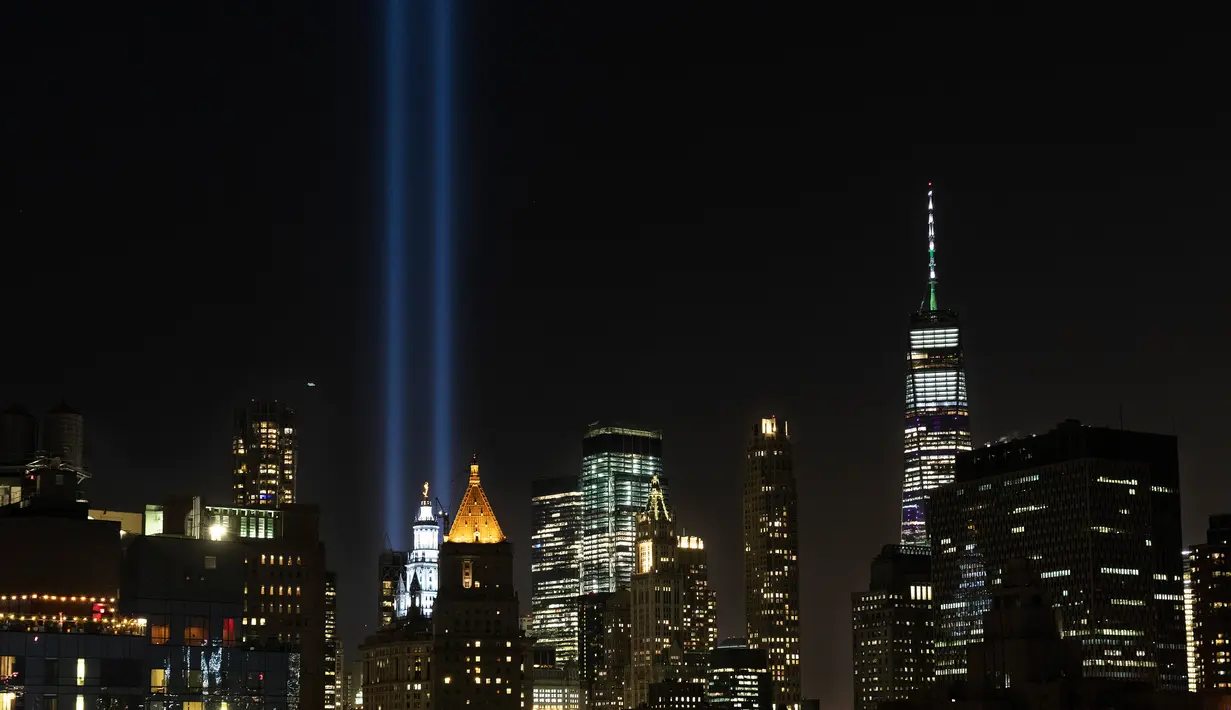 Instalasi cahaya bertajuk 'Tribute in Light' menerangi langit di lower Manhattan, New York, Selasa (10/9/2019). Cahaya kembar berwarna biru tersebut dinyalakan untuk memperingati 18 tahun peristiwa serangan gedung kembar World Trade Center (WTC) pada 11 September 2001 silam. (AP/Mark Lennihan)