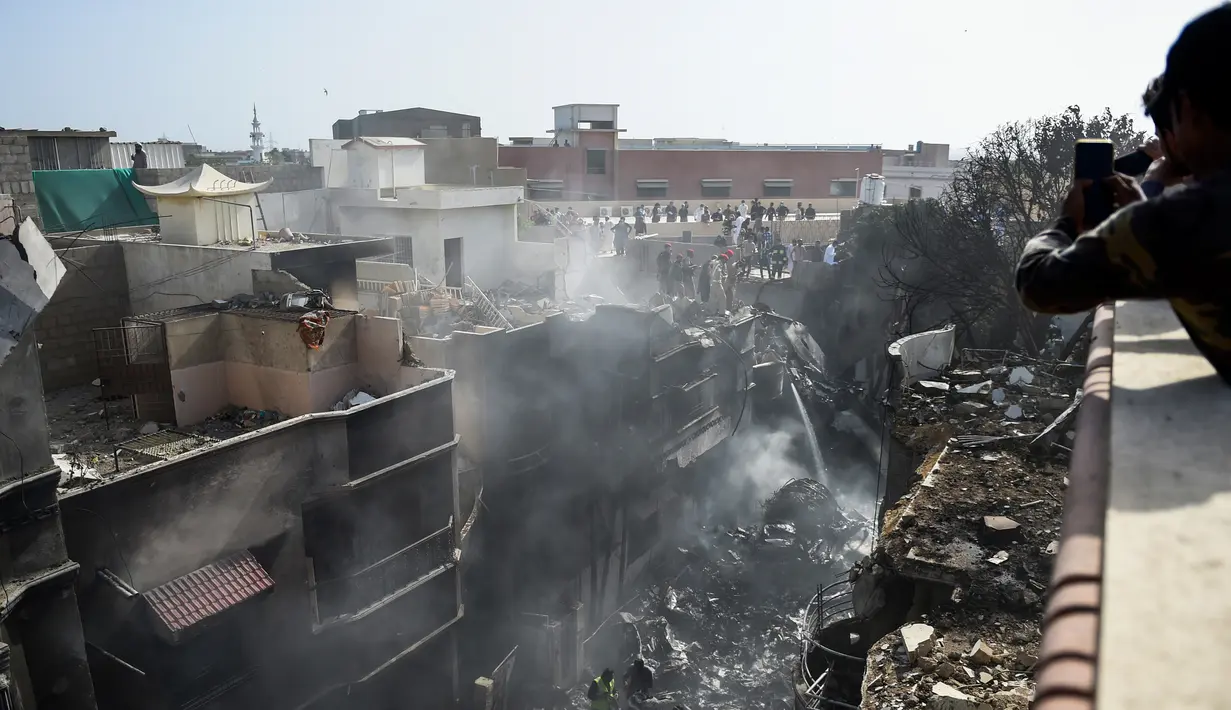 Petugas penyelamat berkumpul di lokasi jatuhnya pesawat Pakistan International Airlines di Karachi, Pakistan, Jumat (22/5/2020). Lokasi kecelakaan berada di perumahan tidak jauh dari Bandara Internasional Jinnah. (Rizwan TABASSUM/AFP)