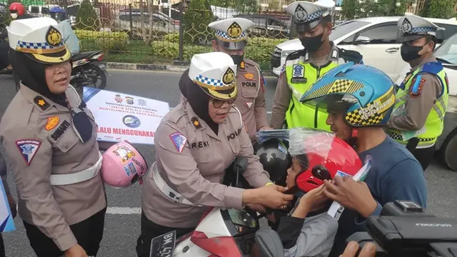 Personel Lalu Lintas Polda Riau menghadiahkan helm kepada anak-anak pada Operasi Zebra Lancang Kuning.