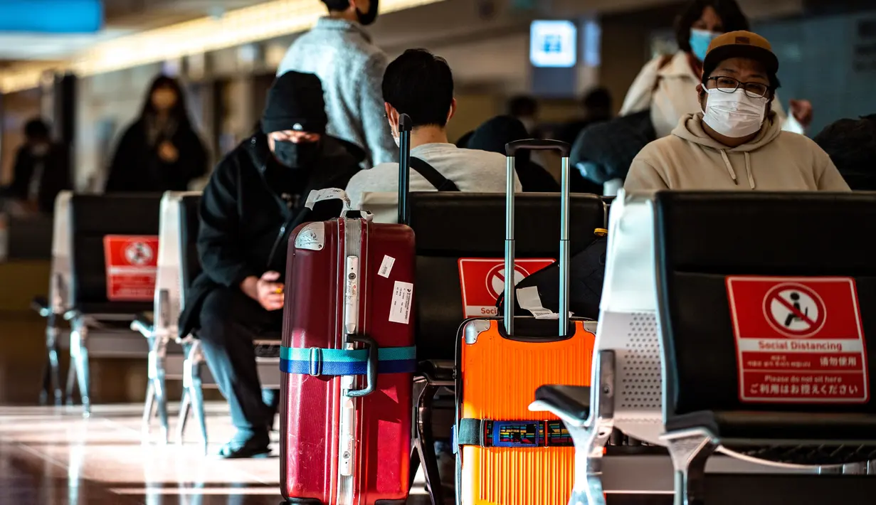 Penumpang duduk di ruang kedatangan di Bandara Internasional Haneda Tokyo, Jumat (18/2/2022). Pemerintah Jepang mengumumkan rencana untuk melonggarkan aturan perbatasan virus bagi pekerja dan pelajar. (AFP/Philip Fong)