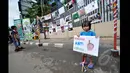 Seorang anak kecil tampak berdiri di depan pameran meme tentang korupsi yang digelar di Jalan MH Thamrin, Jakarta, Minggu (18/1/2015). (Liputan6.com/Miftahul Hayat)