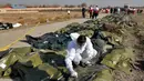 Tim forensik menuliskan sesuatu di kantong jenazah korban jatuhnya pesawat Boeing 737-800 di Shahedshahr, Iran, Rabu (8/1/2020). Pesawat sempat terbakar di udara sebelum akhirnya jatuh di lahan pertanian. (AP Photo/Ebrahim Noroozi)