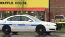 Kendaraan polisi terparkir di lokasi penembakan yang terjadi di  area restoran Waffle House dekat Nashville, Tennessee, Minggu (23/4). Polisi mengidentifikasi pelaku sebagai Travis Reinking (29) dan kini sedang diburu aparat. (AP Photo/Sheila Burke)
