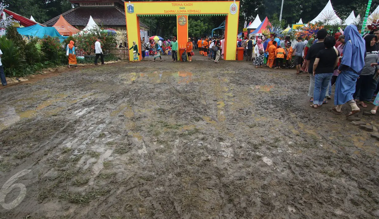 Pengunjung menghindari jalan tanah yang becek pada Festival Lebaran Betawi IX di Lapangan Banteng, Jakarta, Minggu (14/8). Meskipun becek akibat hujan, namun warga tetap antusias mengunjungi festival tahunan tersebut. (Liputan6.com/Immanuel Antonius)
