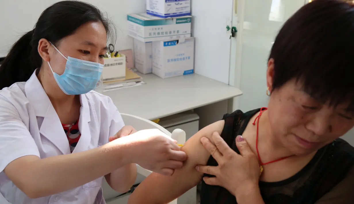 Seorang wanita mendapat suntikan vaksin anti rabies di Pusat Pengendalian dan Pencegahan Penyakit di Huaibei, Selasa (24/7). Salah satu produsen vaksin terbesar di negara itu diketahui memalsukan data produksi dalam pembuatan vaksin rabies. (AFP)
