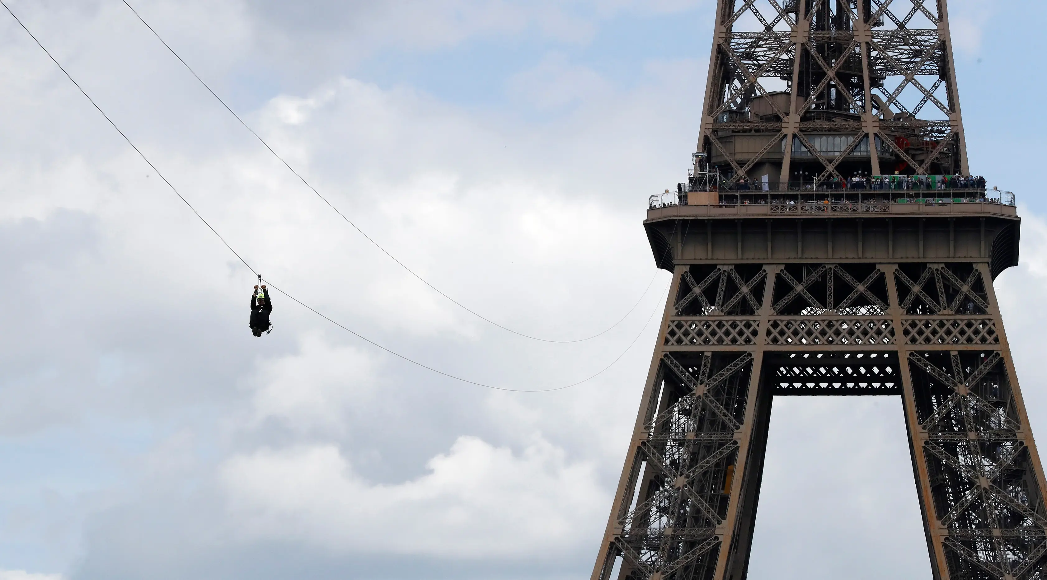 Seorang pengunjung meluncur dengan seutas tali saat melakukan flying fox dari Menara Eiffel di Paris, 5 Mei 2017. Kesempatan ini dibuka untuk umum jelang turnamen tenis French Open agar dapat merasakan bagaimana kecepatan bola tenis (FRANCOIS GUILLOT/AFP)