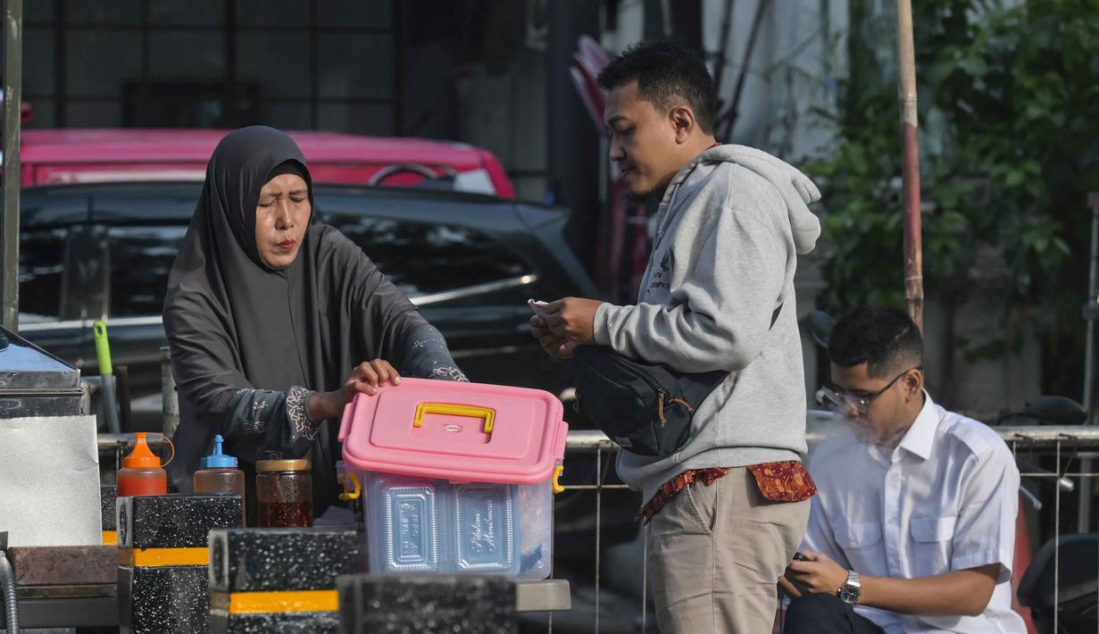 Hal tersebut mengingat sebagian besar pelaku usaha mikro berasal dari kelompok berpenghasilan rendah dan bekerja di sektor informal. Tampak dalam foto, seorang wanita menyajikan sarapan kepada pelanggannya di sebuah warung pinggir jalan, Jakarta, Senin 4 Mei 2026. (BAY ISMOYO/AFP)