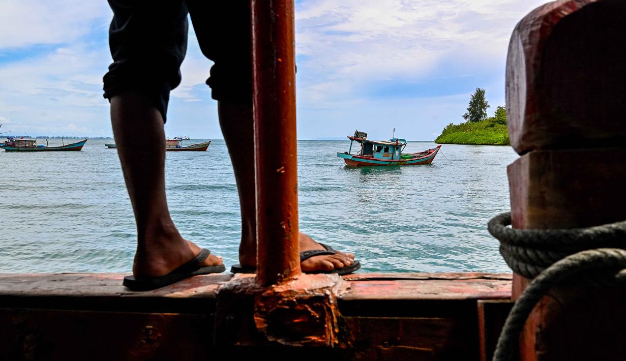 Penyelesaian didasarkan pada pertimbangan data historis, kultural, dan hukum, termasuk merujuk pada Undang-Undang Nomor 24 Tahun 1956 tentang Pembentukan Daerah Otonom Provinsi Aceh. Tampak dalam foto, seorang pria memandang ke arah perahu nelayan yang berlabuh di lepas Pulau Panjang, yang pernah menjadi objek sengketa batas pulau antara Aceh dan Sumatera Utara, di Singkil, Provinsi Aceh Selatan, pada Rabu 12 November 2025. (CHAIDEER MAHYUDDIN/AFP)