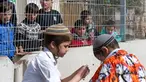 Anak-anak Palestina menyaksikan warga Yahudi merayakan Hari Purim di Jalan al-Shuhada, Kota Hebron, Tepi Barat, Kamis (1/3). Hari Purim diperingati untuk memperingati pembebasan orang-orang Yahudi dari genosida Persia kuno. (AFP PHOTO/HAZEM BADER)