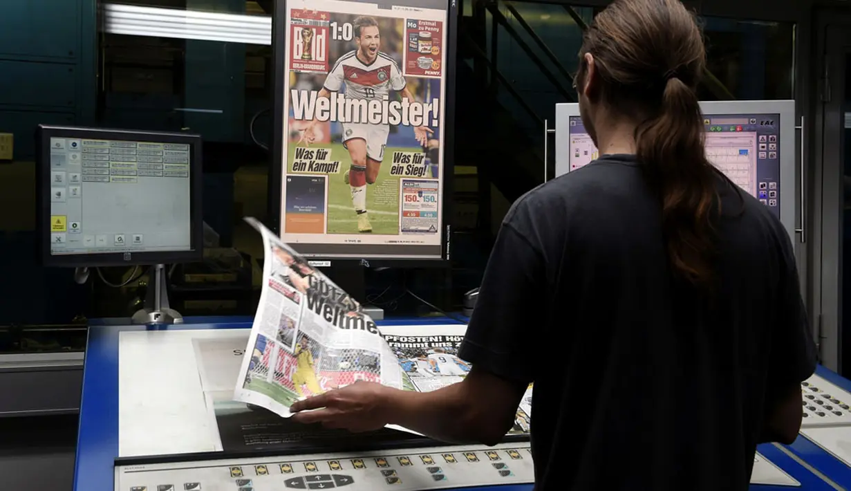 Salah satu petugas percetakan mengecek kualitas gambar surat kabar "Bild" yang dipenuhi foto-foto selebrasi pemain Timnas Jerman saat menjadi juara Piala Dunia 2014, Berlin, (14/7/2014). (REUTERS/Fabian Bimmer)