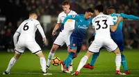 Pemain Arsenal, Mesut Ozil berusaha merebut bola dengan kawalan pemain Swansea City dalam laga pekan ke-25 Premier League 2017-2018 di Liberty Stadium, Selasa (30/1). Arsenal dipaksa menyerah Swansea City 1-3. (Nick Potts/PA via AP)