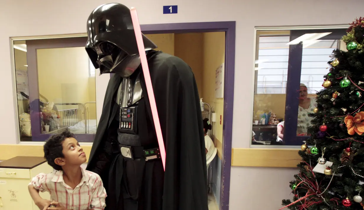 Seorang cosplayer berpakaian Darth Vader berbincang dengan seorang anak saat acara amal oleh El Salvador Star Wars fan club di Rumah Sakit Benjamin Bloom Anak Nasional di San Salvador, El Salvador (14/12). (REUTERS/Jose Cabezas)