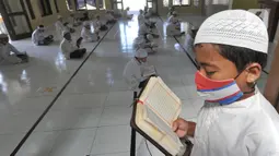 Santri berusia belasan tahun membaca Al quran atau tadarus bersama-sama dengan menerapkan jaga jarak di Masjid Daarul Qu'ran Pesantren Al Kautsar, Cibinong, Bogor, Kamis (7/5/2020). Kegiatan Khatam Al quran tersebut dilakukan rutin di setiap bulan Ramadan. (merdeka.com/Arie Basuki)