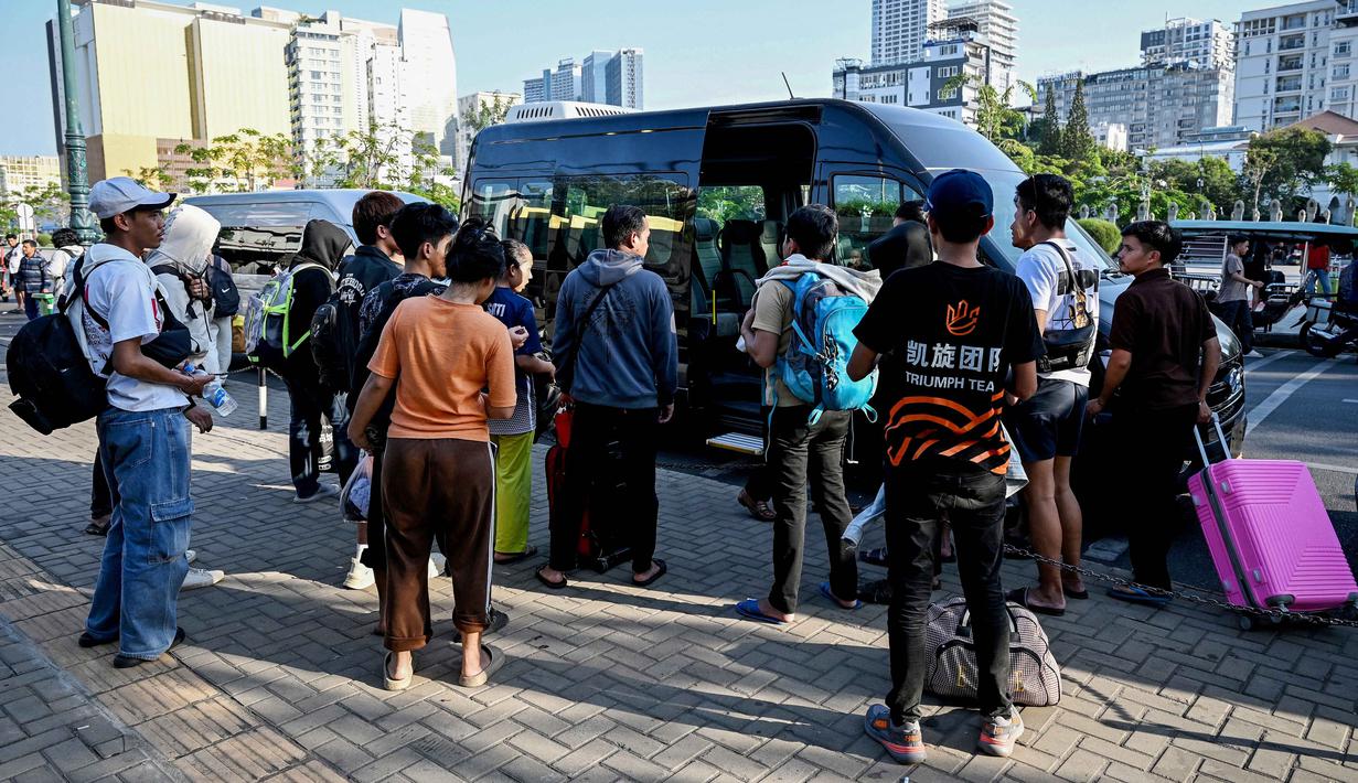 KBRI di Phnom Penh juga berkoordinasi dengan otoritas Kamboja, termasuk kepolisian dan imigrasi guna mempercepat proses pemulangan para WNI. Tampak dalam foto, orang-orang bersiap menaiki kendaraan di depan Kedutaan Besar Republik Indonesia (KBRI) di Phnom Penh, Kamboja, pada Rabu 21 Januari 2026. (TANG CHHIN Sothy/AFP)