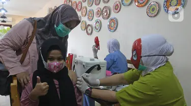 Seorang anak disuntik vaksin covid-19 oleh tenaga kesehatan bertopeng superhero saat vaksinasi anak usia 6-11 tahun di RSIA Tambak, Jakarta, Rabu (22/12/2021). Penggunaan topeng superhero dimaksudkan untuk menarik minat anak-anak yang mengikuti vaksinasi. (lLiputan6.com/Herman Zakharia)