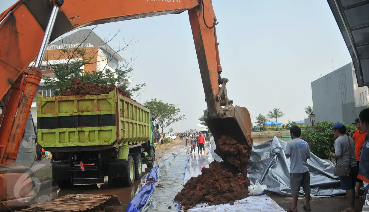 Alat berat menurunkan tanah untuk membuat tanggul di kawasan Perumahan Pantai Mutiara, Jakarta, (4/6). Tingginya pasang air laut menyebabkan tanggul di Jalan Mutiara 1, Pluit, Penjaringan, sepanjang sekitar 50 meter jebol. (Liputan6.com/Gempur M Surya)