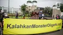 Aktivis Greenpeace membentangkan spanduk saat aksi di depan Gedung DPR RI, Jakarta, Selasa (5/10/2021). Dalam aksinya, mereka membawa gurita raksasa sebagai simbol oligarki serta menyerukan kepada pemerintah agar serius mengatasi pandemi dan memberantas korupsi energi. (Liputan6.com/Faizal Fanani)