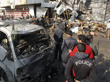 Sebuah mobil rusak akibat ledakan bom di pasar sayur Jumila di Baghdad, Irak (8/1). Terjadi sebuah serangan bom bunuh diri di bagian timur dari ibukota Irak, Baghdad yang menewaskan belasan orang. (AFP/Sabar Arar)