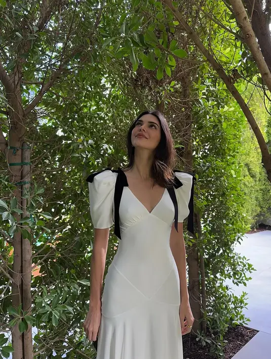 Ia mengenakan gaun v-neck panjang dengan bahu tegak berwarna putih [@kendalljenner]