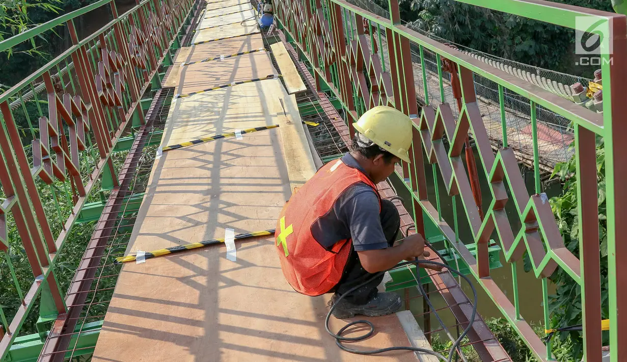 Pekerja menyelesaikan pembangunan jembatan gantung yang diberi julukan Indiana Jones di Srengseng Sawah, Jagakarsa, Jakarta, Jumat (3/8). Pemprov DKI membangun jembatan Indiana Jones karena yang lama sudah tidak layak. (Liputan6.com/Immanuel Antonius)