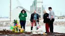 Sebuah keluarga menempatkan salib yang terbuat dari tongkat hoki untuk memberi penghormatan kepada korban kecelakaan bus di Provinsi Saskatchewan, Kanada (9/4). (Jonathan Hayward/The Canadian Press via AP)