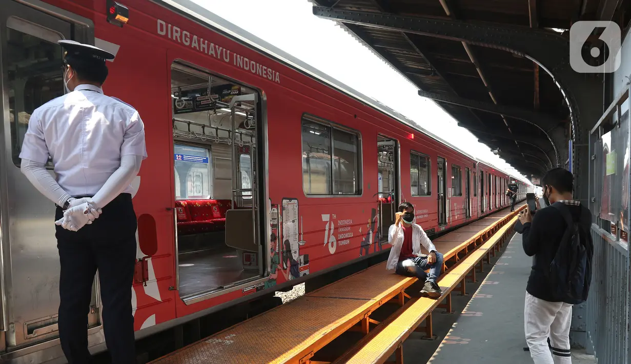 Seorang pria foto di samping Gerbong KAI Commuter bertemakan Kemerdekaan Republik Indonesia ke-76 terpasang di gerbong yang membawa penumpang di Stasiun Kota, Jakarta, Selasa (17/8/2021). (Liputan6.com/Herman Zakharia)