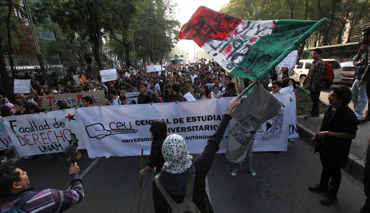 Bendera Meksiko dikibarkan saat unjuk rasa menolak kenaikan harga BBM, Mexico City, Meksiko (9/1). Akibat demonstrasi ini sekitar 1500 warga Meksiko ditahan karena melakukan penjarahan. (AP Photo/Marco Ugarte)