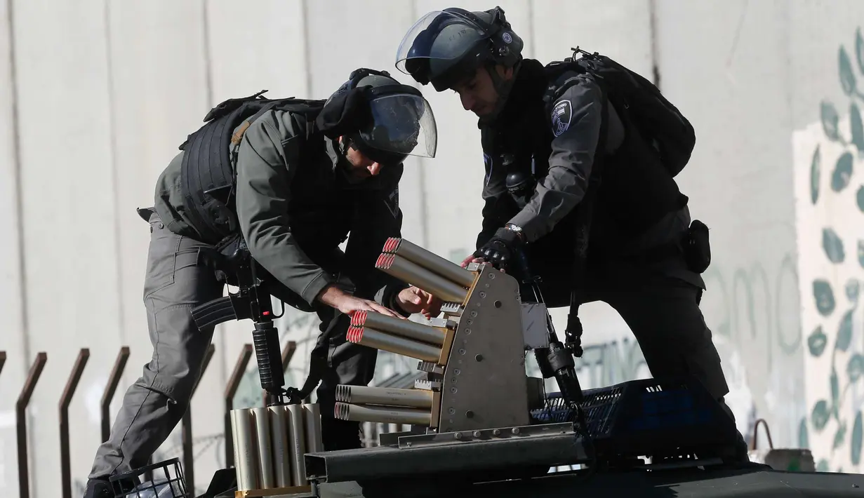 Dua polisi Israel bersiap menembakan gas air mata saat bentrok dengan warga Palestina di kota Bethlehem, Tepi Barat, (7/12). (AP Photo/Nasser Shiyoukhi)