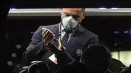Seorang staf Ludogorets mengenakan masker sebelum turun dari bus menuju stadion San Siro, Milan, Italia (27/2/2020). Penggunaan masker dilakukan untuk mencegah Virus Korona yang telah menyebabkan 11 orang meninggal dunia di Italia. (Ludogorets FC via AP)