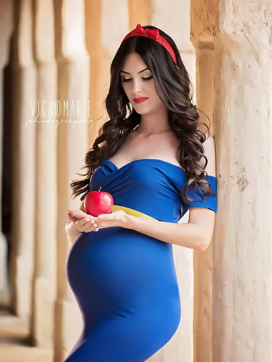 Wanita yang sedang hamil besar ini berpose memegang buah apel layaknya film Snow White atau Putri Salju. Dalam konsep pemotretan ini, Vic dan Marie menampilkan para ibu yang sedang hamil besar bak putri Disney. (Instagram/vicandmariephotography)