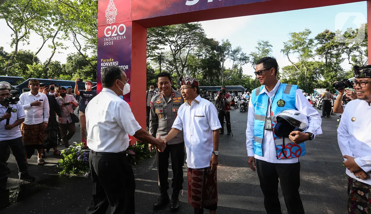 Gubernur Bali I Wayan Koster berjabat tangan menyambut Menteri Energi dan Sumber Daya Mineral (ESDM) Arifin Tasrif saat Parade Konversi Sepeda Motor BBM Ke Listrik di Nusa Dua, Bali, Kamis (1/9/2022). Parade motor listrik tersebut adalah rangkaian memperkuat pelaksanaan G20 dalam transisi energi berkelanjutan. (Liputan6.com/Johan Tallo)