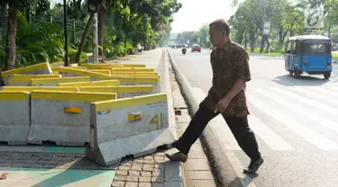 Pejalan kaki menghindari pembatas jalan yang menutupi trotoar di Jalan Medan Merdeka Utara, Jakarta, Rabu (3/7/2019). Pembatas jalan yang berada tidak pada tempatnya tersebut mengganggu pejalan kaki karena menutupi badan trotoar. (Liputan6.com/Immanuel Antonius)