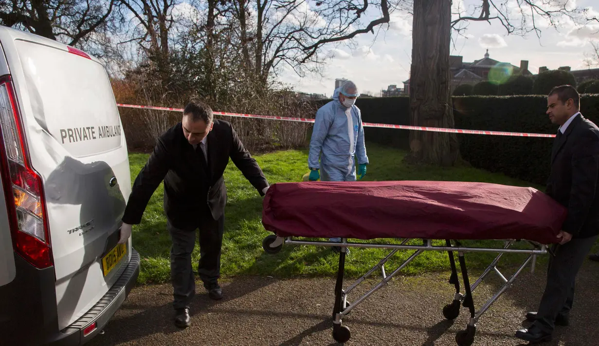 Petugas memasukkan jasad pria yang tewas usai membakar diri ke dalam ambulans, di dekat Istana Kensington, London, Inggris, Selasa (9/2). Pria 40 tahun itu membakar diri di dekat tempat tinggal Pangeran Willian dan Kate Middleton. (REUTERS/Neil Hall)
