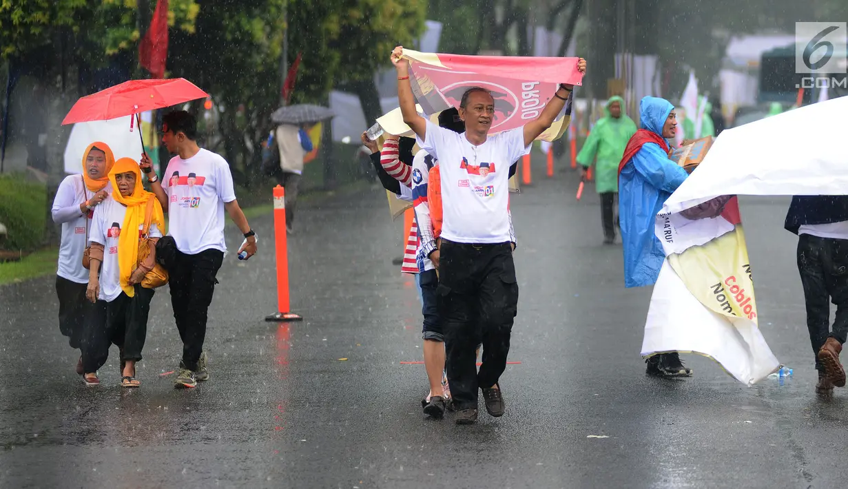 Pendukung calon presiden nomor urut 01 Joko Widodo diguyur hujan saat tiba di Sentul International Convention Center, Bogor, Jawa Barat, Minggu (24/2). Jokowi akan menyampaikan keberhasilan kebijakan pemerintah. (Liputan6.com/Herman Zakharia)