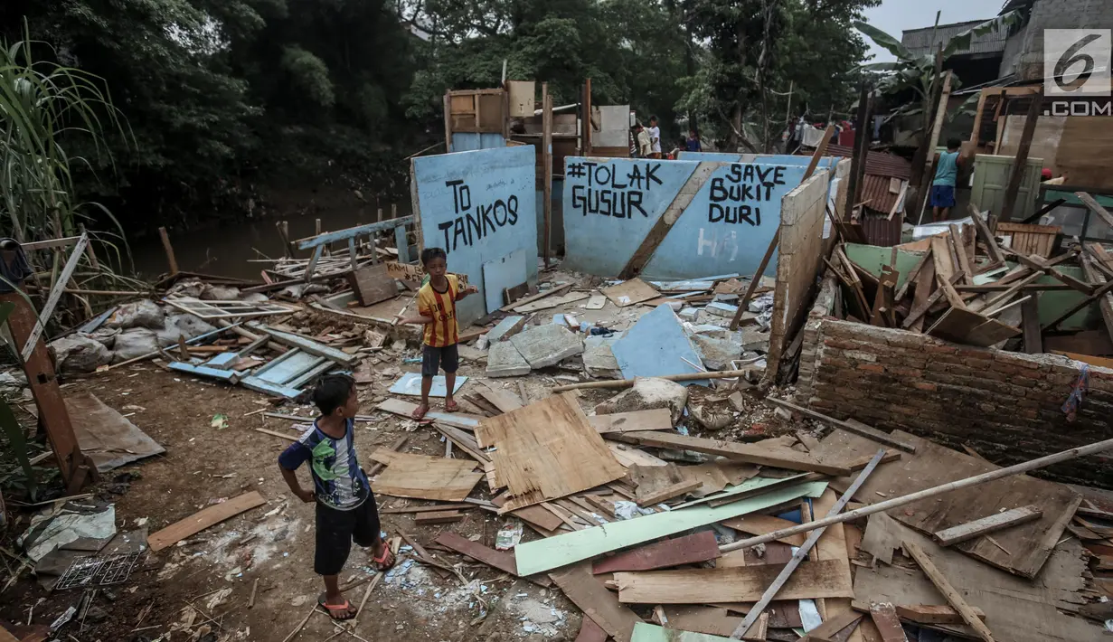 Dua orang bocah bermain di bongkaran bangunan yang terletak di bantaran sungai Ciliwung, Bukit Duri, Jakarta, Rabu (5/7). Pemerintah akan melaksanakan rencana penertiban bangunan di bantaran sungai Ciliwung. (Liputan6.com/Faizal Fanani)