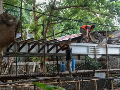 Pekerja menyelesaikan proyek pembangunan jembatan penghubung antarkampung di kawasan Pondok Pinang, Jakarta, Jumat (13/12/2019).  Jembatan yang menghubungkan permukiman di daerah Pondok Pinang dengan kawasan Bintaro tersebut ditargetkan rampung pada akhir Desember. (Liputan6.com/Faizal Fanani)