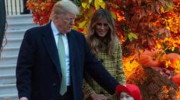 Presiden Amerika Serikat (AS) Donald Trump dan Ibu Negara Melania Trump memberikan permen kepada anak-anak selama yang hadir acara trick-or-treat pada perayaan Halloween di Gedung Putih, Washington, Minggu (28/10). (NICHOLAS KAMM / AFP)
