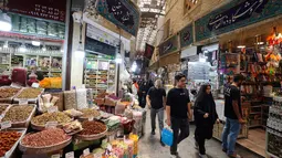 Orang-orang berjalan melewati toko-toko di Tajrish Bazaar, ibu kota Iran, Teheran, pada 30 Juni 2025. (ATTA KENARE/AFP)