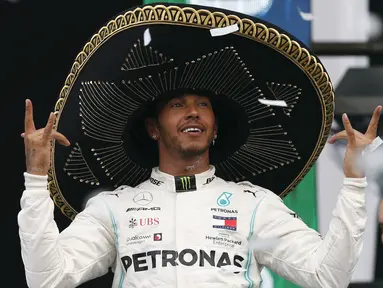 Pembalap Mercedes dari Inggris, Lewis Hamilton mengenakan topi sombrero merayakan keberhasilannya menjuarai balapan GP Meksiko di Autodromo Hermanos Rodriguez, Mexico City (28/10/2019). Kemenangan ini mendekatkan Hamilton ke titel juara dunia F1 2019. (AP Photo/Rebecca Blackwell)
