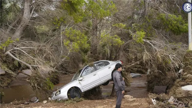 Sebuah mobil yang sebagian tergantung di pohon setelah terbawa air banjir di Derna, Libya. (Pemerintah Libya melalui AP)