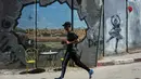 Ajang tahunan ini menekankan solidaritas dan hak untuk bergerak bagi warga Palestina. Tampak dalam foto, seorang pria berlari melewati tembok pemisah Israel saat ia berkompetisi dalam Maraton Palestina di kota Betlehem, Tepi Barat, Jumat 8 Mei 2026. (AP Photo/Mahmoud Illean)