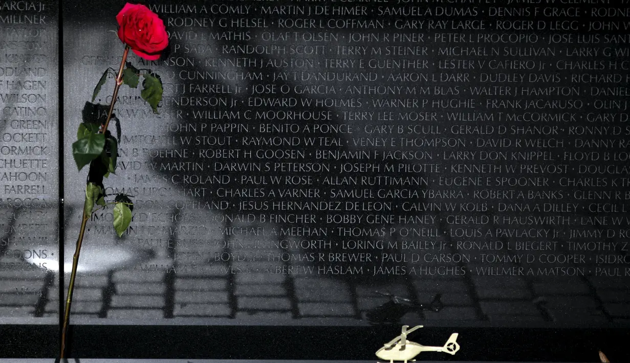 Setangkai bunga mawar dan helikopter mainan tampak di tembok Vietnam Veterans Memorial pada Hari Veteran di Washington DC, Amerika, Rabu (11/11). Hari Veteran adalah hari libur nasional untuk menghormati jasa para tentara Amerika. (REUTERS/Carlos Barria)