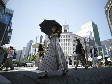 Orang-orang berjalan di atas penyeberangan pejalan kaki di bawah terik matahari di Tokyo, Selasa (28/6/2022). Pemerintah Jepang mengeluarkan peringatan untuk kemungkinan pemadaman listrik di wilayah Tokyo pada hari Senin (27/6), meminta kantor dan penduduk untuk menghemat energi karena wilayah ibu kota dilanda panas terik. (AP Photo/Eugene Hoshiko)